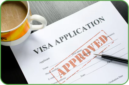 a visa application form with a large red stamp across it that reads "APPROVED." The form is partially filled out with fields for the applicant's name, phone number, email address, and other personal information. There is a black pen resting on the form, and a cup of coffee is placed nearby on the table. The image has a green border around it.